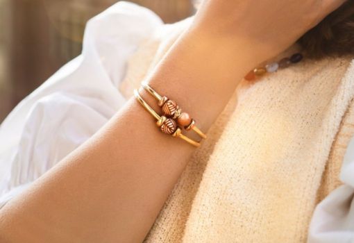 Close up of two gold plated bangles styled with barrel beads
