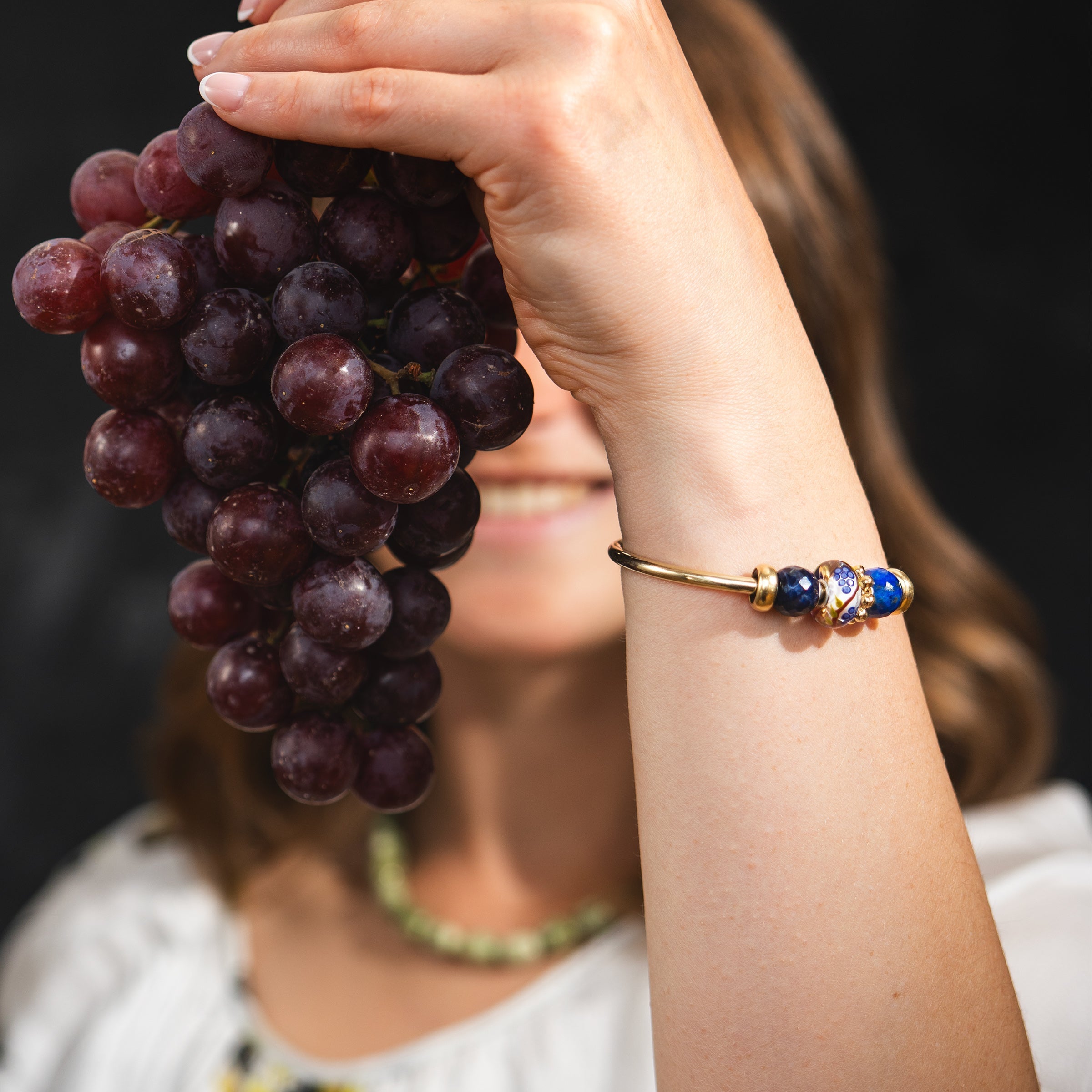 Model holding grapefruits wearing gold plated bangle with beads