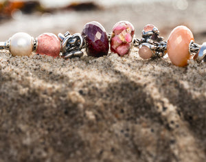 Trollbeads foxtail bracelet with a ruby and gemstones in pink and red hues, along with glass and silver beads 