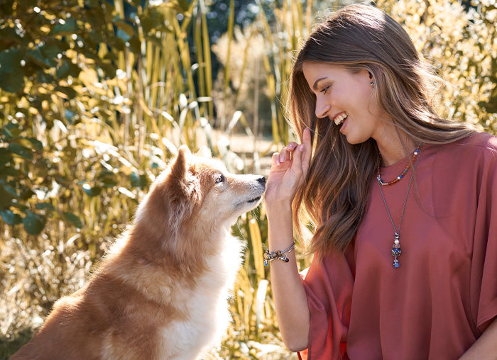 Woman in nature playing with her dog wearing Trollbeads Jewellery